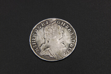 Old Austrian silver coin on black background - obrazy, fototapety, plakaty