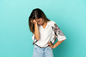 Young woman over isolated blue background with headache