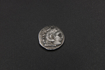 Silver ancient greek coin on black background