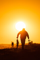 Silhouette of a fisherman carrying a large fish back from the beach at sunset. Jones Beach, Long Island New York