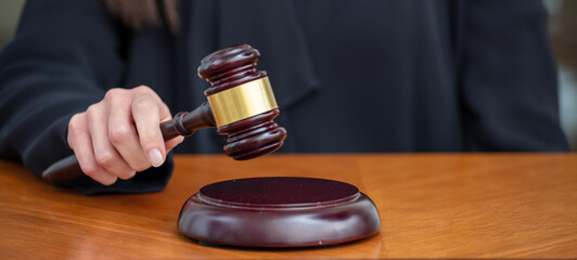 Judge female hand hold a gavel on law court bench, overhead. Justice and punishment concept