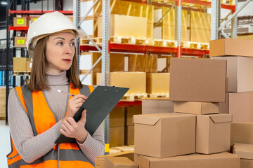 Businesswoman in warehouse. Woman writes on clipboard. Business owner in company warehouse. Girl...