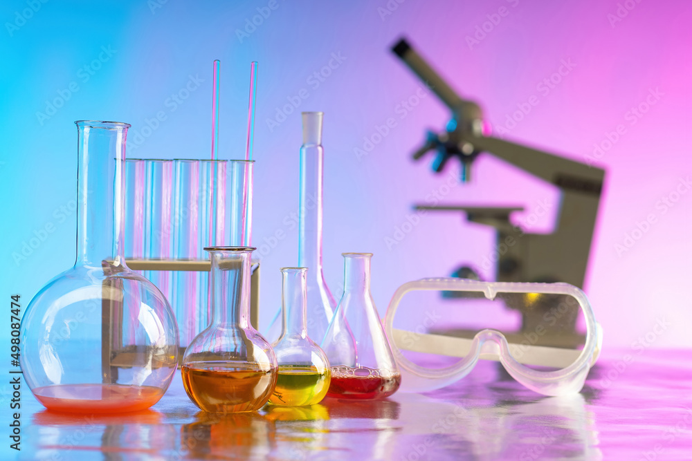 Poster laboratory glassware. test tubes with multi-colored liquids. flasks with reagents in front of micros
