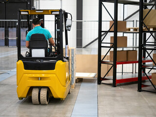 Man drives forklift in warehouse. Man lifts pallet with load using forklift. Concept equipment for warehouse loading. Technique for transporting goods in warehouse. Loader driver career