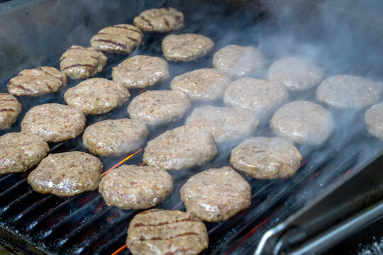 Grilled meatballs,tomatos ,peppers and mushrooms shown on a grill while cooking with somoke on them