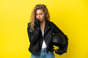 Young blonde woman with a motorcycle helmet isolated on yellow background having doubts