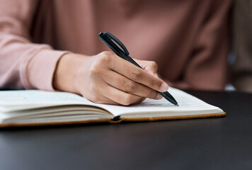 Never give up on your goals. Shot of an unrecognisable woman writing in a notebook while working from home.