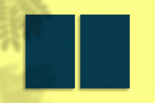 Top View Blank Blue Business Card Mockup With Leaf Shadows Overlays On Yellow Background.