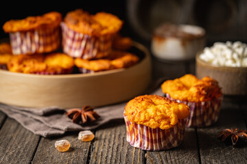 Sweet homemade cottage cheese muffins with pumpkin on dark wooden background
