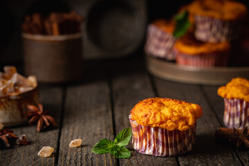 Sweet homemade cottage cheese muffins with pumpkin on dark wooden background