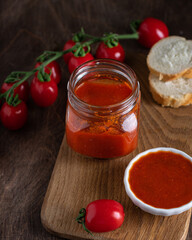 Fototapeta na wymiar Homemade tomato chutney in glass jar on wooden background. Selective focus. Copy space