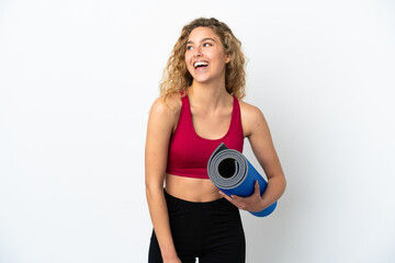 Young sport blonde woman going to yoga classes while holding a mat isolated on white background...