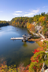 Small fishing dock and gazebo on a peaceful lake, surrounded by colorful leaves and fall foliage....