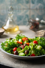 Classic vegetable salad with fresh olives, tomatoes, cucumbers and olive oil on gray background.