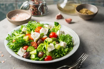 Rolgordijnen Classic vegetable salad with fresh olives, tomatoes, cucumbers, greek cheese feta and olive oil on gray background. © petrrgoskov