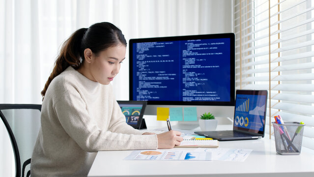 Asia young business woman sit busy at home office desk work code on desktop reskill upskill for job career remote self test IT deep tech ai design skill online html text for cyber security workforce.