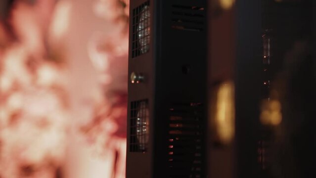 Vertical lighting system with halogen bulbs behind protective grilles smoothly turns on and off. Pink backlighting of wall with flowers in background and reframing with white rotating concert beam.