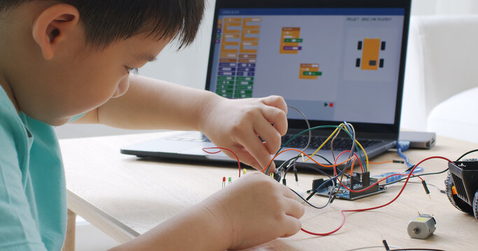 Asia home school young small kid happy smile self study online lesson excited make AI circuit toy. STEM STEAM digital scratch class on laptop screen for active children play arduino enjoy fun hobby.