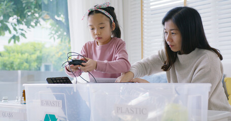 Mom teach Gen Z preteen girl kid dump paper glass can e-waste bag in reuse bin recycle bank help climate change social issue in asia people. Trash sorting clean eco green zero waste fun learn at home.