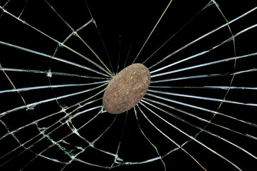 The thrown stone hits and shatters the window glass