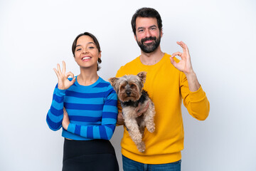 Young hispanic woman holding a dog isolated on white background showing an ok sign with fingers