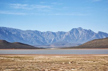 Where has the rain gone. Shot of a desolate landscape during the day with a small dried out dam in the middle.