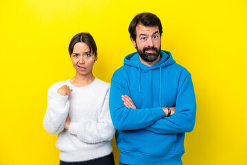 Young caucasian couple isolated on yellow background annoyed angry in furious gesture