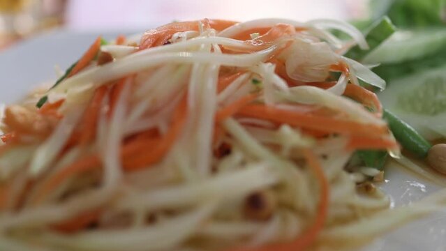 Close up of fresh yummy delicious Thai traditional popular street food spicy green papaya salad or Som Tam in dish
