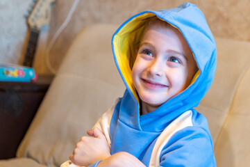 A cheerful smiling caucasian boy in a hood looks up, emotions of joy and good mood.