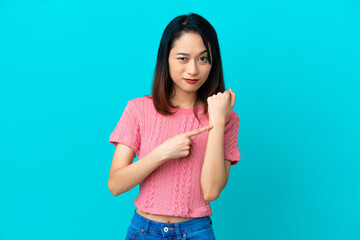 Young Vietnamese woman isolated on blue background making the gesture of being late