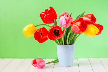 Bouquet of beautiful tulips in a vase on a light green background