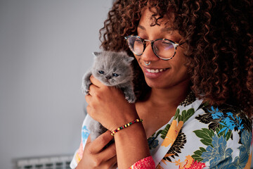 young black woman with curly hair with a little exotic grey cat