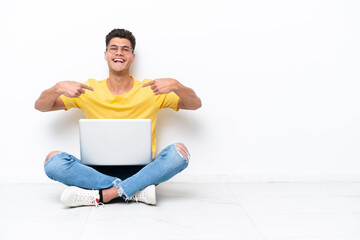Young man sitting on the floor isolated on white background proud and self-satisfied