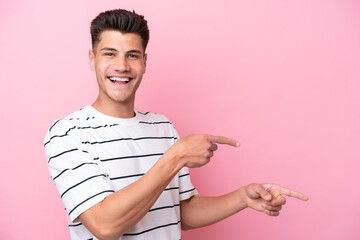 Young caucasian man isolated on pink background pointing finger to the side and presenting a product