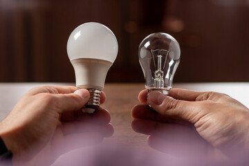 Two lamps in the hands of a man. Incandescent light bulb and LED light bulb in your hands.