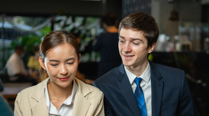 Young businessman looking at businesswoman, smile, wear suit, sitting with hotel cafe background. Young man and woman work business or shopping online in hotel cafe