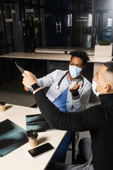 Fototapeta premium African doctor show x-ray asian patient. Black surgeon analyzing x ray and diagnosis patient in medical clinic.