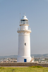 Fototapeta na wymiar Paphos lighthouse on the Mediterranean sea coast. White lighthouse in archeological park in Paphos city.