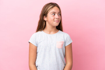 Fototapeta premium Little caucasian girl isolated on pink background making doubts gesture looking side