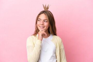 Little princess with crown isolated on pink background looking to the side and smiling