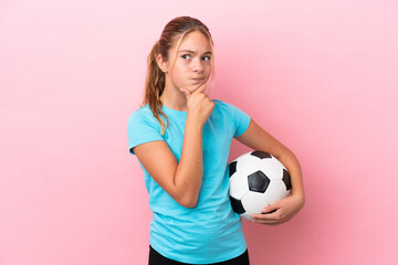 Little football player girl isolated on pink background having doubts and thinking