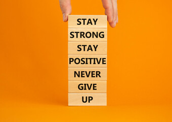 Never give up symbol. Wooden blocks with concept words Stay strong stay positive never give up. Beautiful orange background. Copy space. Businessman hand. Motivational business never give up concept.