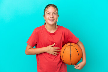 Little caucasian girl playing basketball isolated on blue background smiling a lot