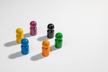 A group of wooden figurines in different colors standing in a circle for the concepts of teamwork, diversity, equality and business