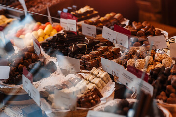 Plates with chocolate balls, truffles, candies in the window of a candy store. Chocolate workshop.