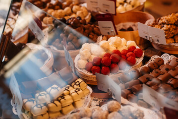 Plates with chocolate balls, truffles, candies in the window of a candy store. Chocolate workshop.