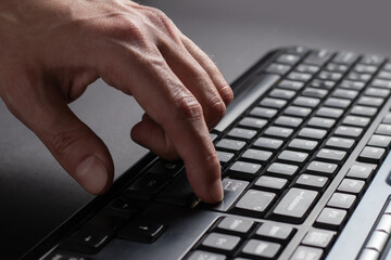 Finger presses the enter button. Typing male hands. Black keyboard button close up
