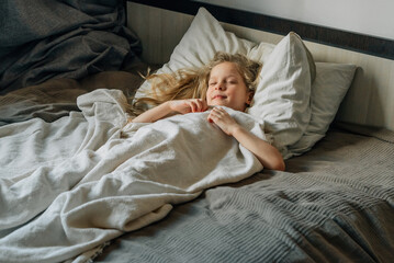little beautiful long-haired girl preschooler wakes up in the morning, sleeps with a smile on her face