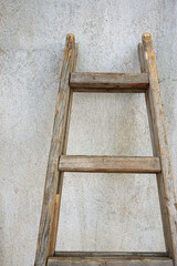 Old wooden weathered ladder leaning against the wall.