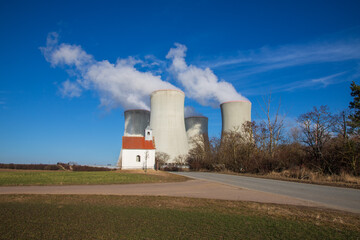 Fototapeta na wymiar Dukovany Nuclear Power Plant in the Czech Republic, Europe. Smoke cooling towers. There are clouds in the sky. In the background the nature of the Highlands.